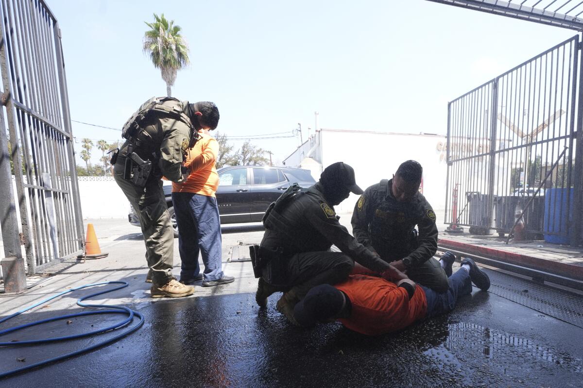 Immigration agents detain two men at a car wash.