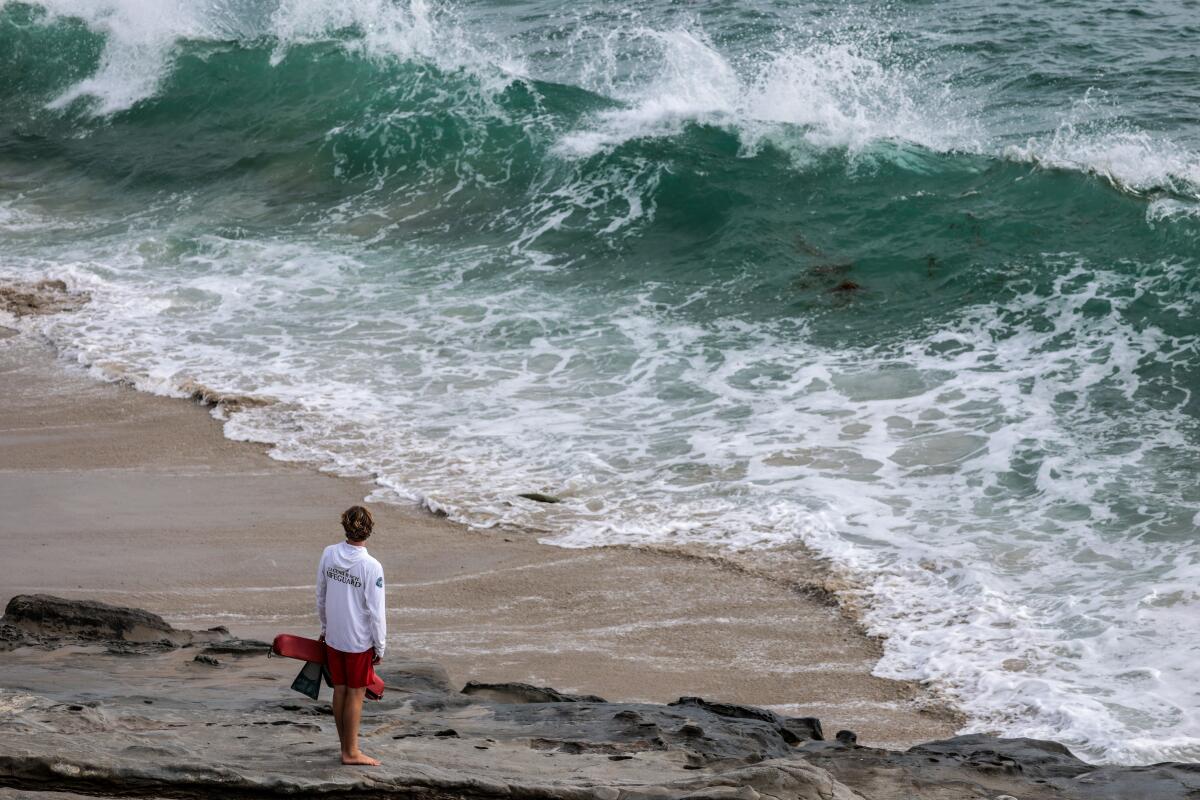 A lifeguard stands in front of a large wave