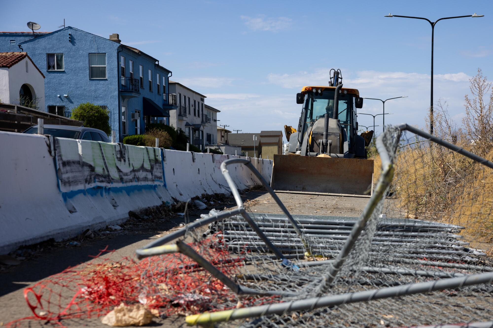 A backhoe sits idle in a construction site next to houses along Crenshaw Boulevard