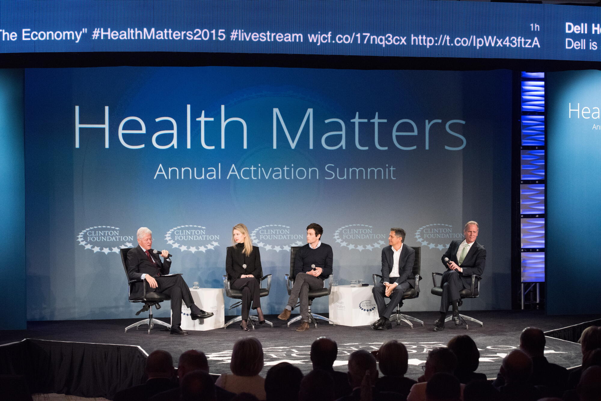 Five people seated onstage during a conference