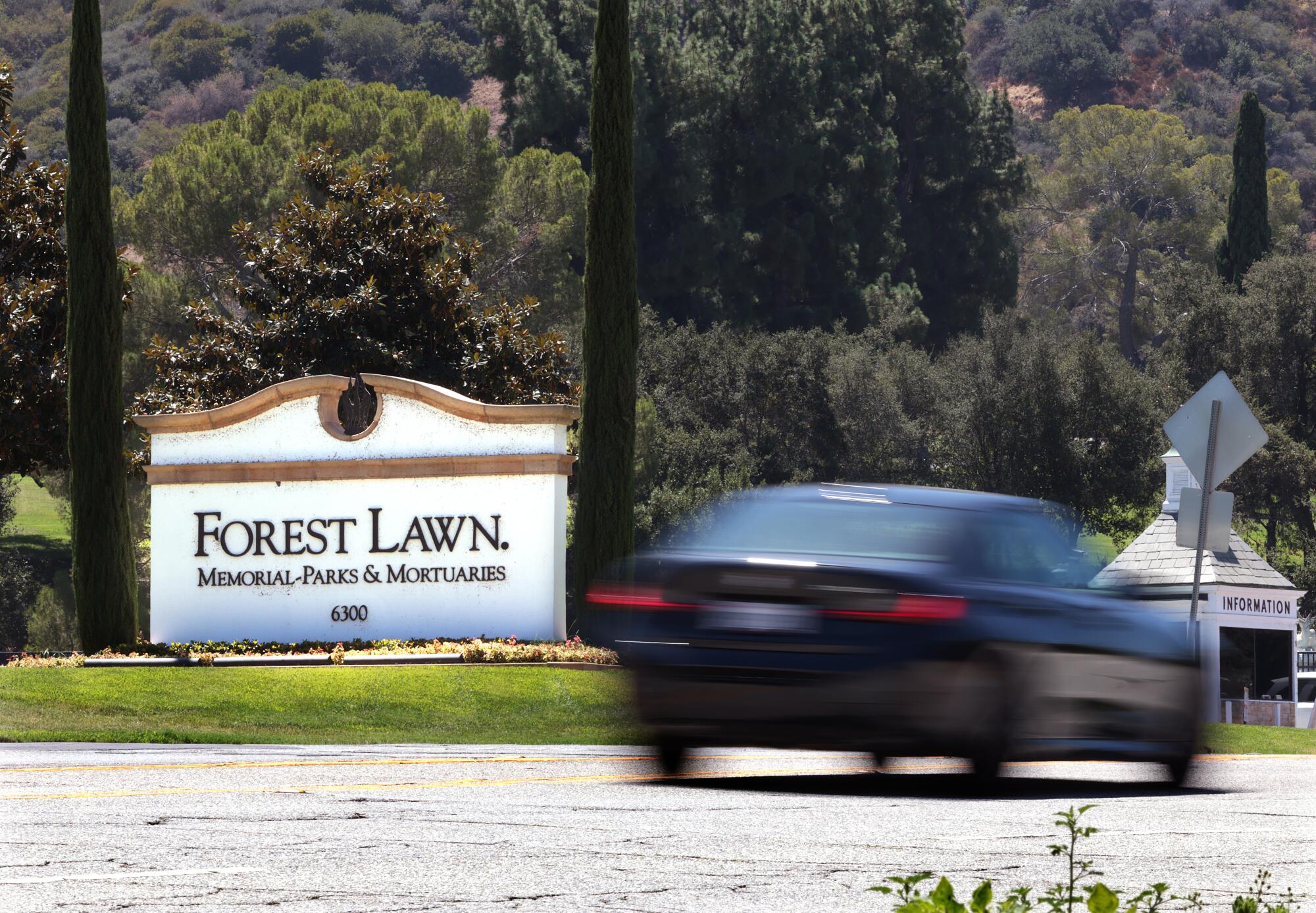 A vehicle passes a sign that says "Forest Lawn."