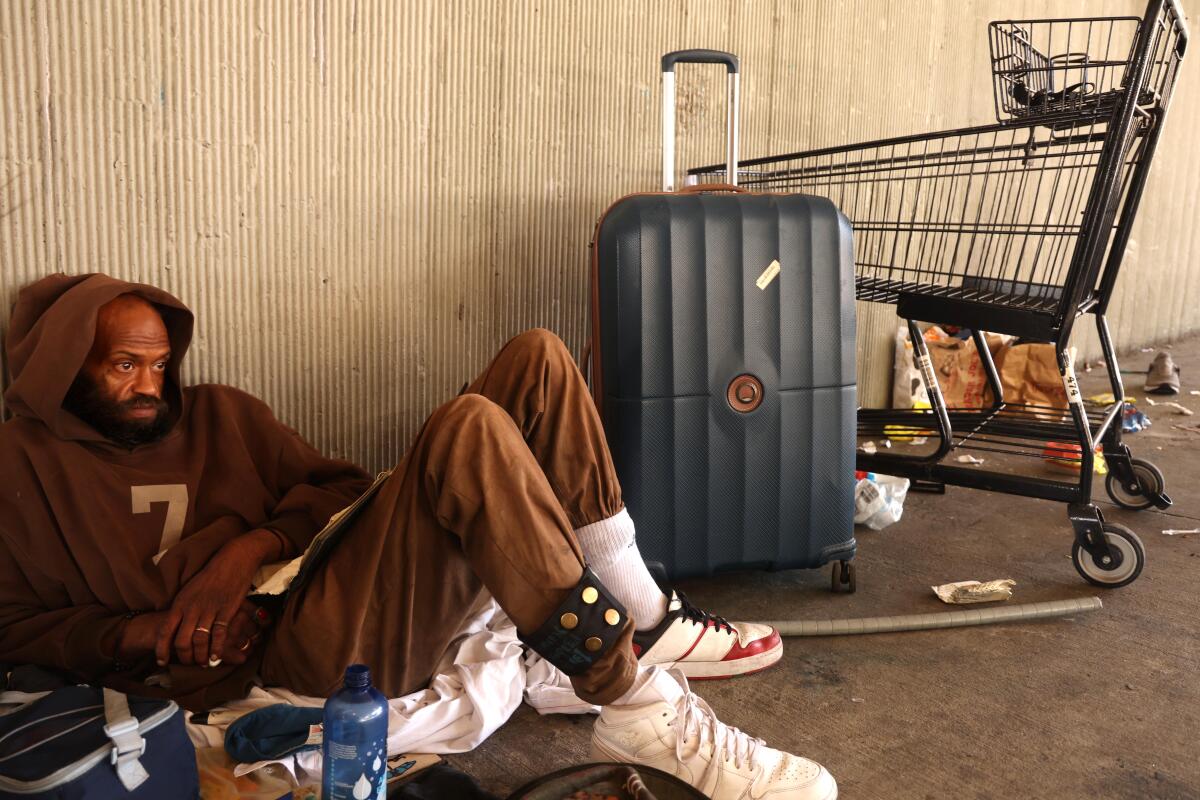 A man sits with his some of his belongings on Cahuenga Boulevard under the 101 Freeway.