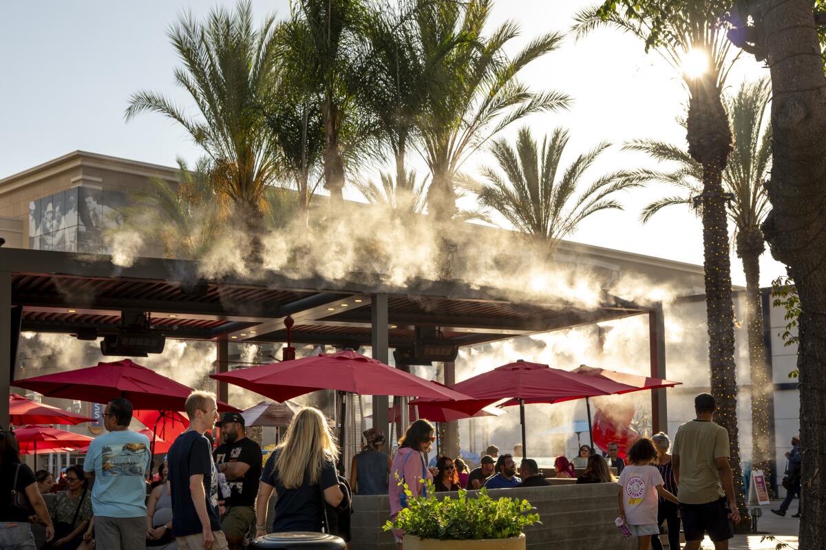 Pedestrians walk past a restaurant with misters on the pedestrian mall on Palm avenue in the downtown Burbank.