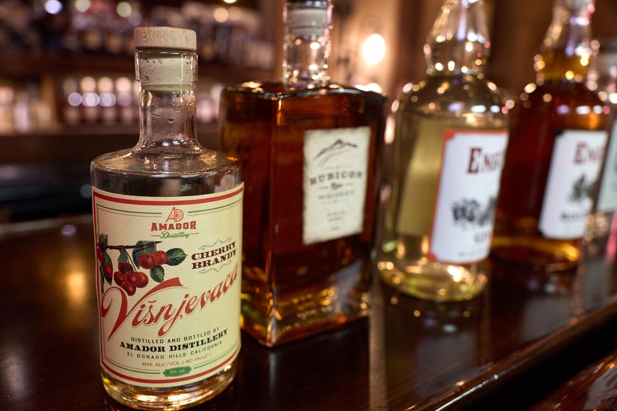 A bottle of Amador Distillery's cherry brandy sits on a bar alongside other spirits, including bottles of bourbon and gin.