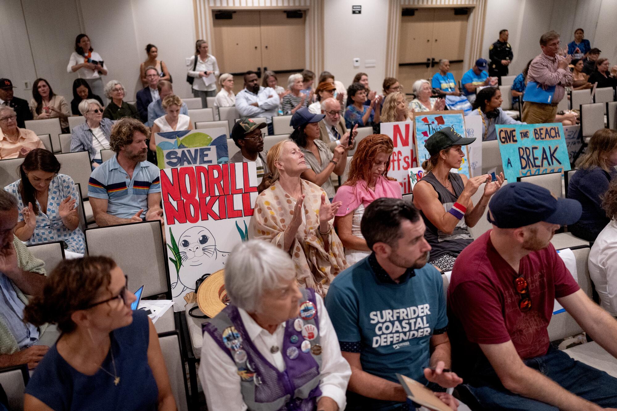 People clap during a public hearing.