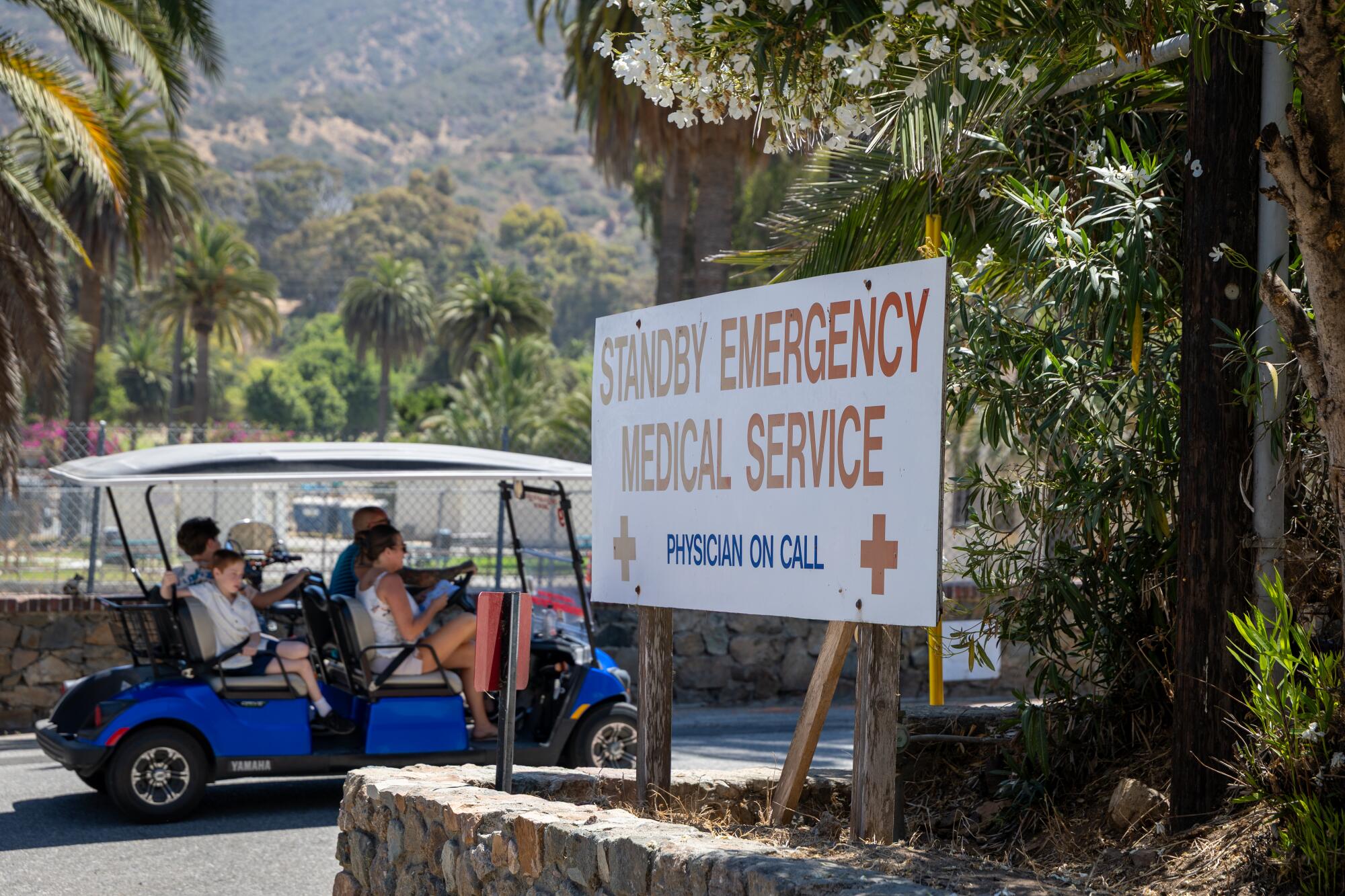 People travel in a golf cart past Catalina Island Health.