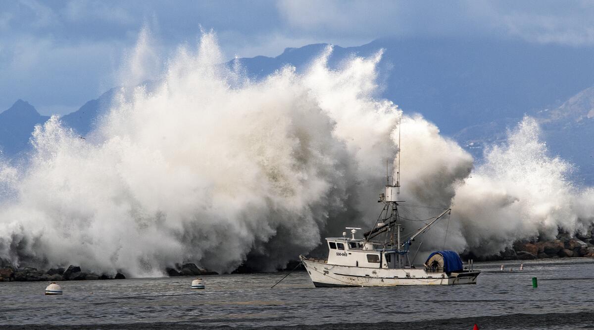 A large wave crashes over the rocks as viewed from the Redondo Beach Pier