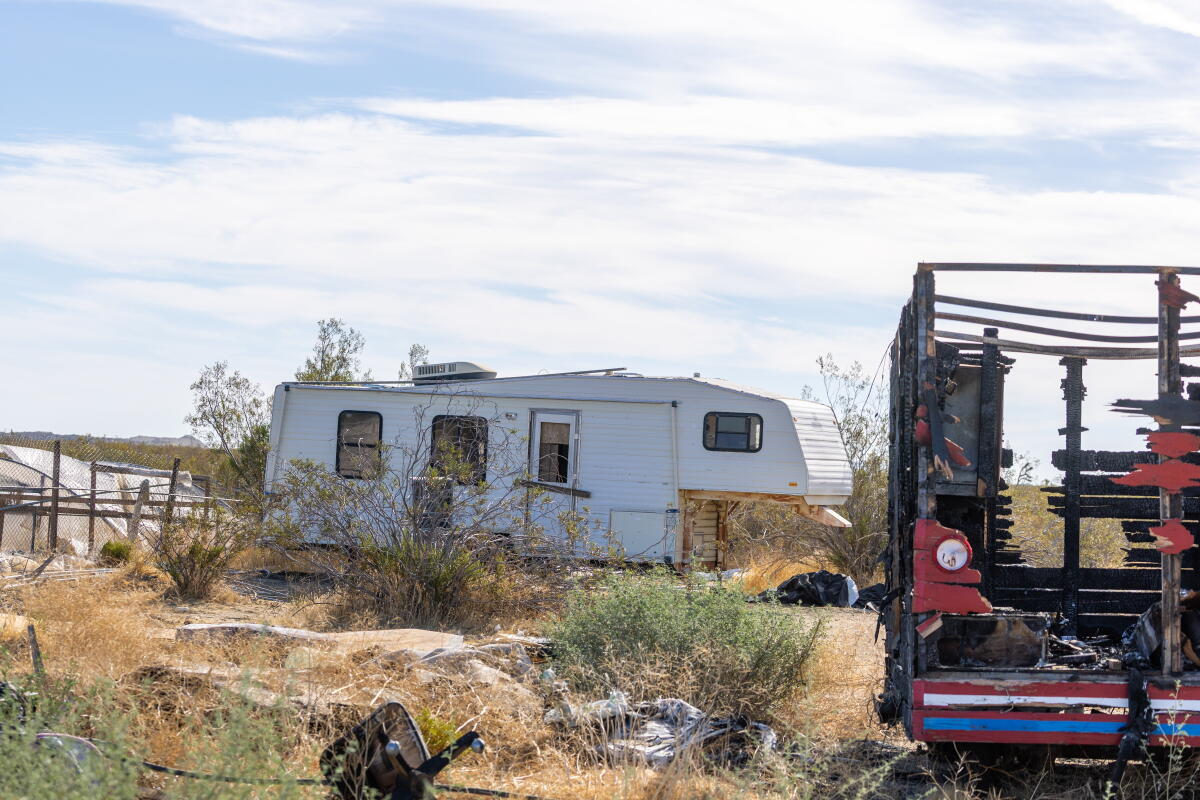 A white RV near a wreck of a vehicle