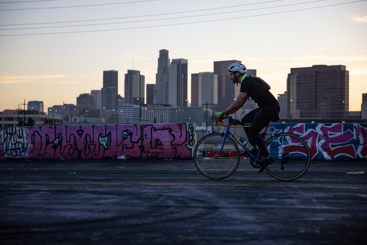 A man cycles past graffiti next to the Los Angeles River.