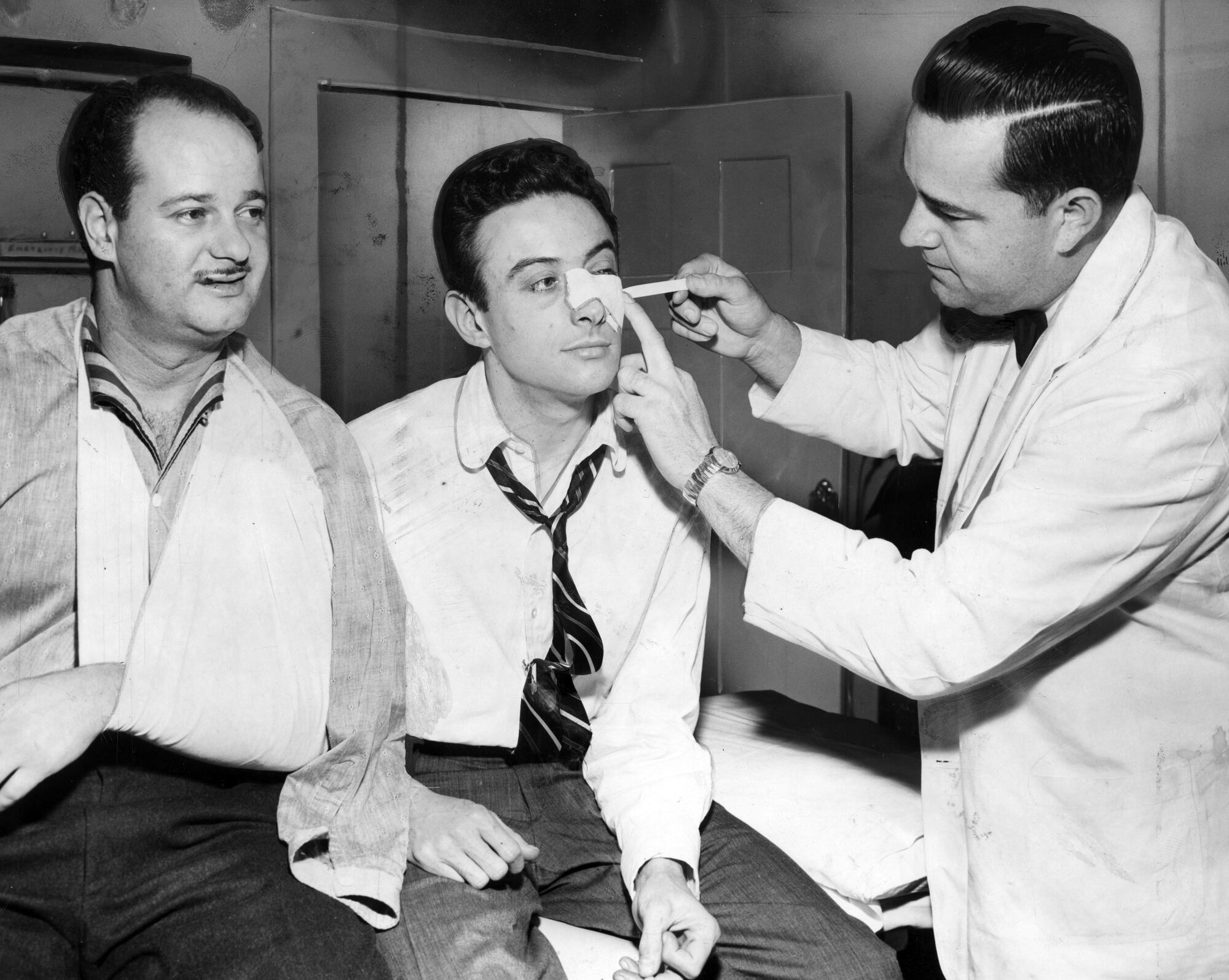 A doctor treats Lenny Bruce for a facial injury.