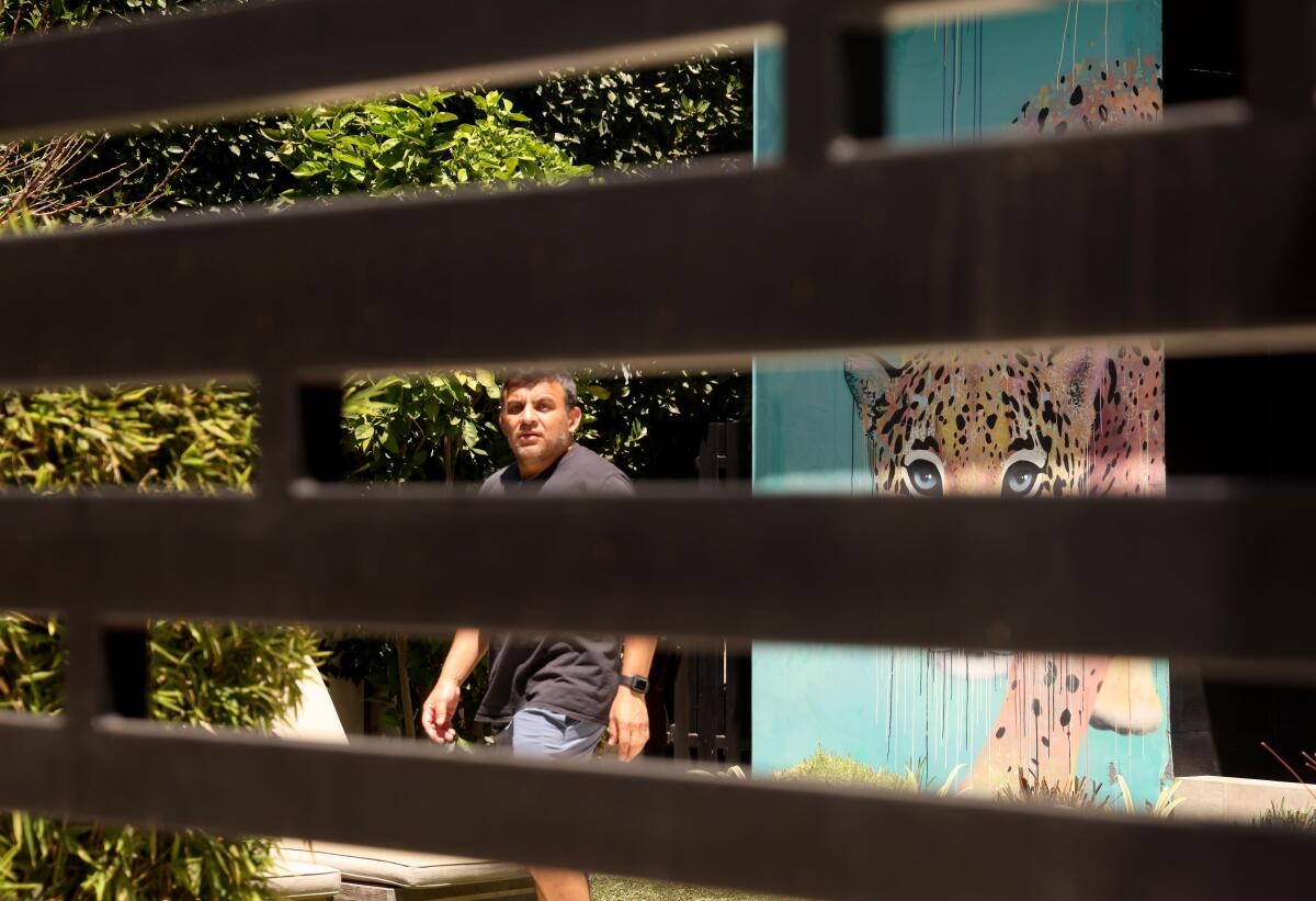 A man walks through the front yard of a home that features a mural of a tiger in the Sunset Square neighborhood.