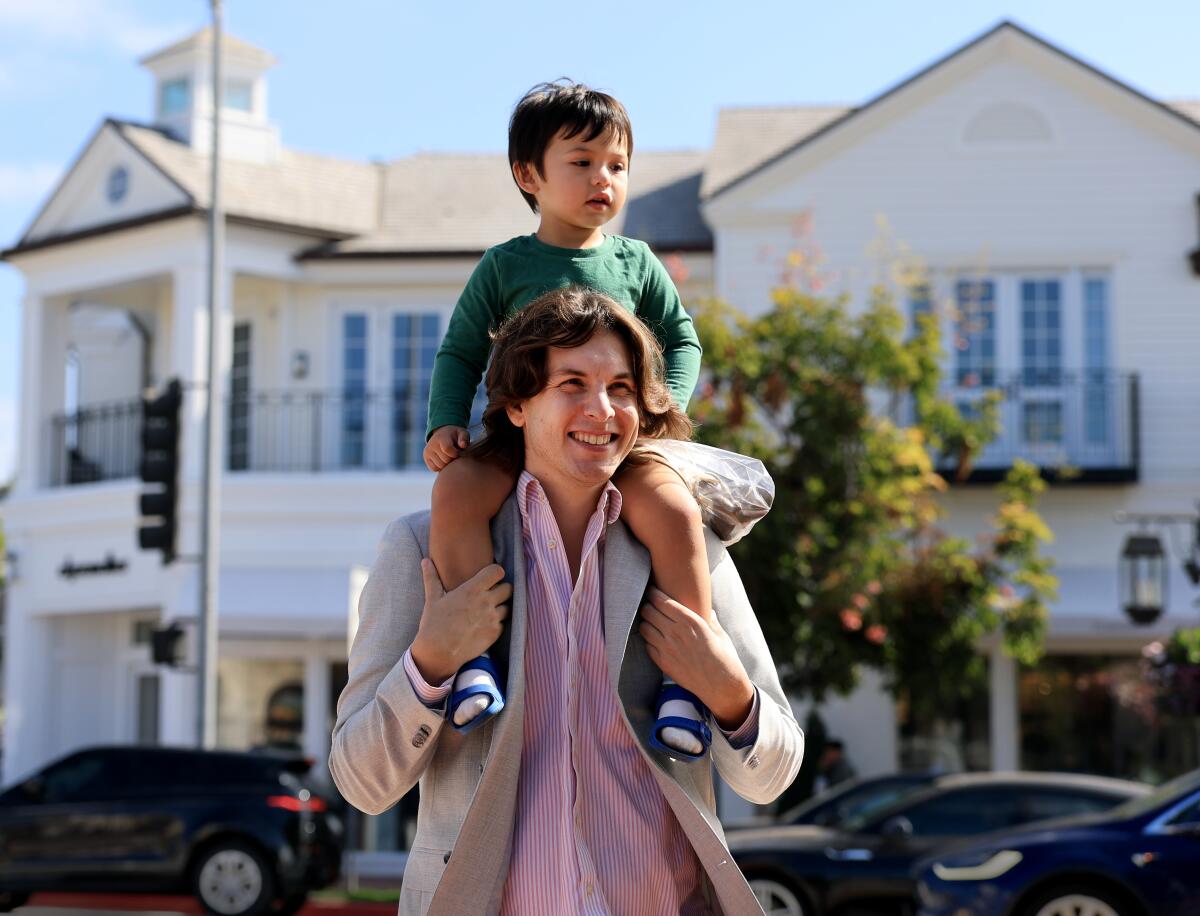 Yves Felker and his son Adam Felker, 2, join crowds attending the grand reopening of Rick Caruso's Palisades Village