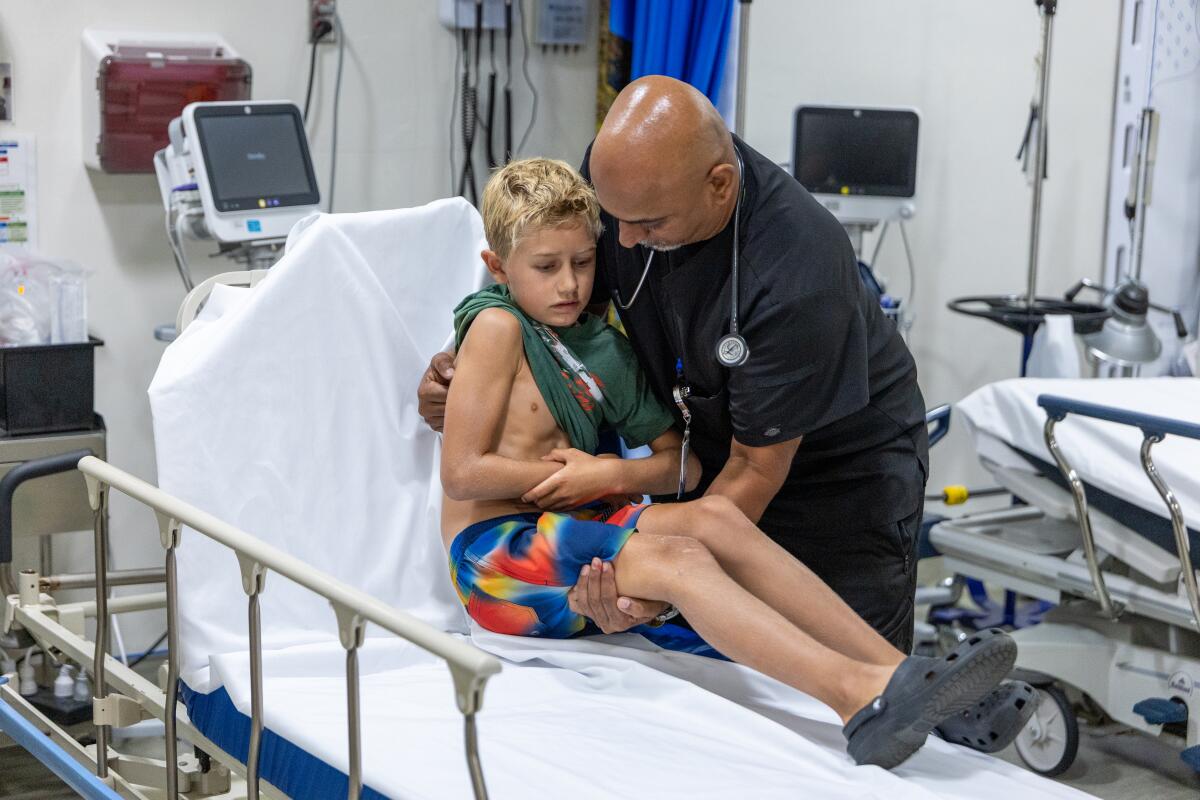 A registered nurse helps an arm injury patient into an emergency room bed at Catalina Island Health