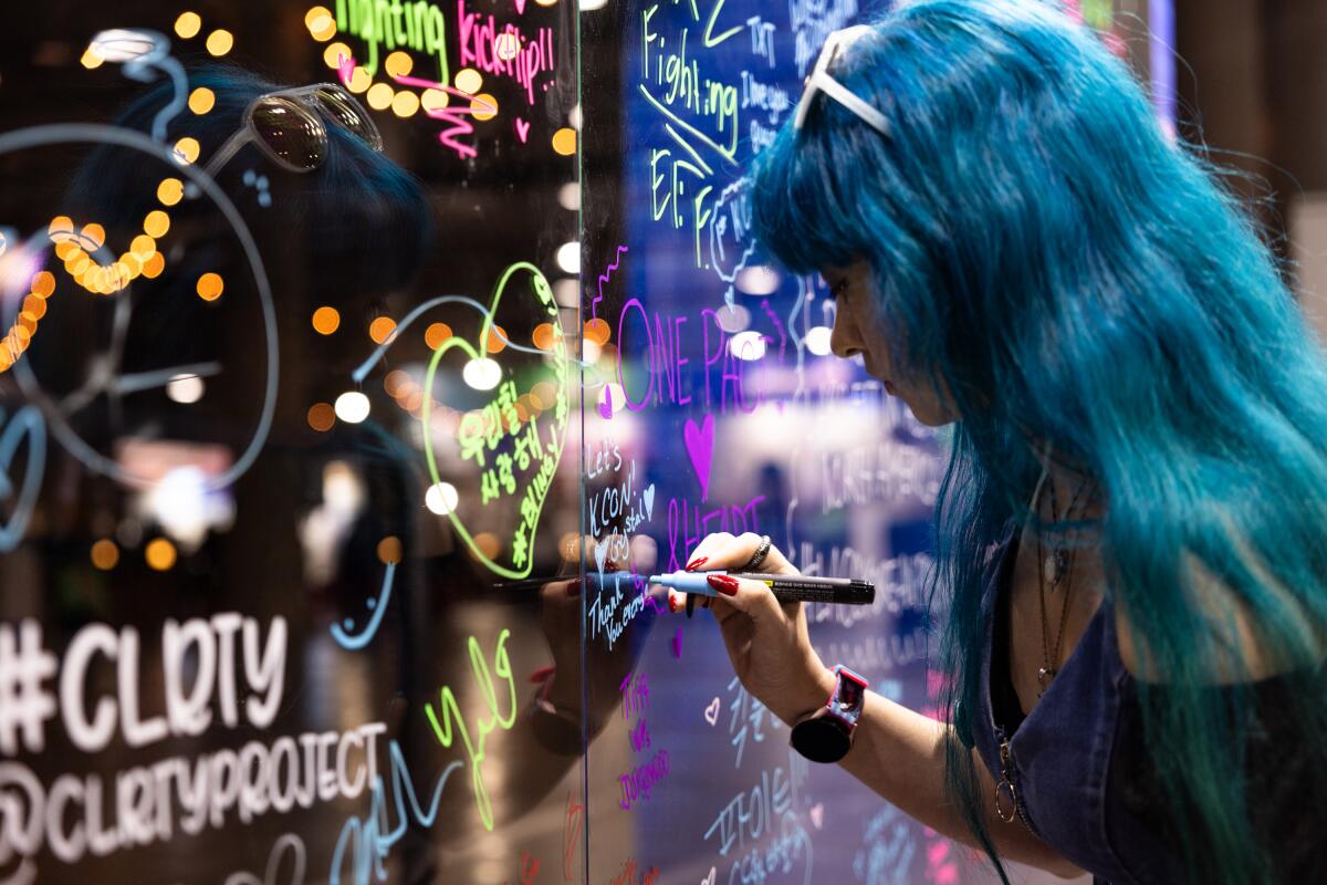  Crystal Ramirez writes a thank you note on a fan wall during day one of KCON at the Los Angeles Convention Center.