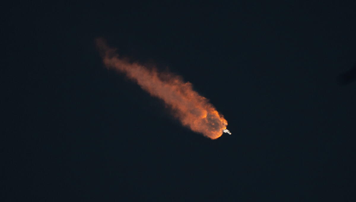 A launching rocket disappears into a dark sky.