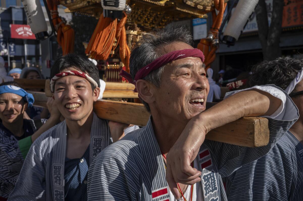 Men carry a portable shrine through the streets. 