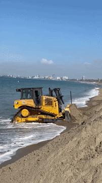 A bulldozer moves sand along the Long Beach shore in an effort to battle beach erosion. 