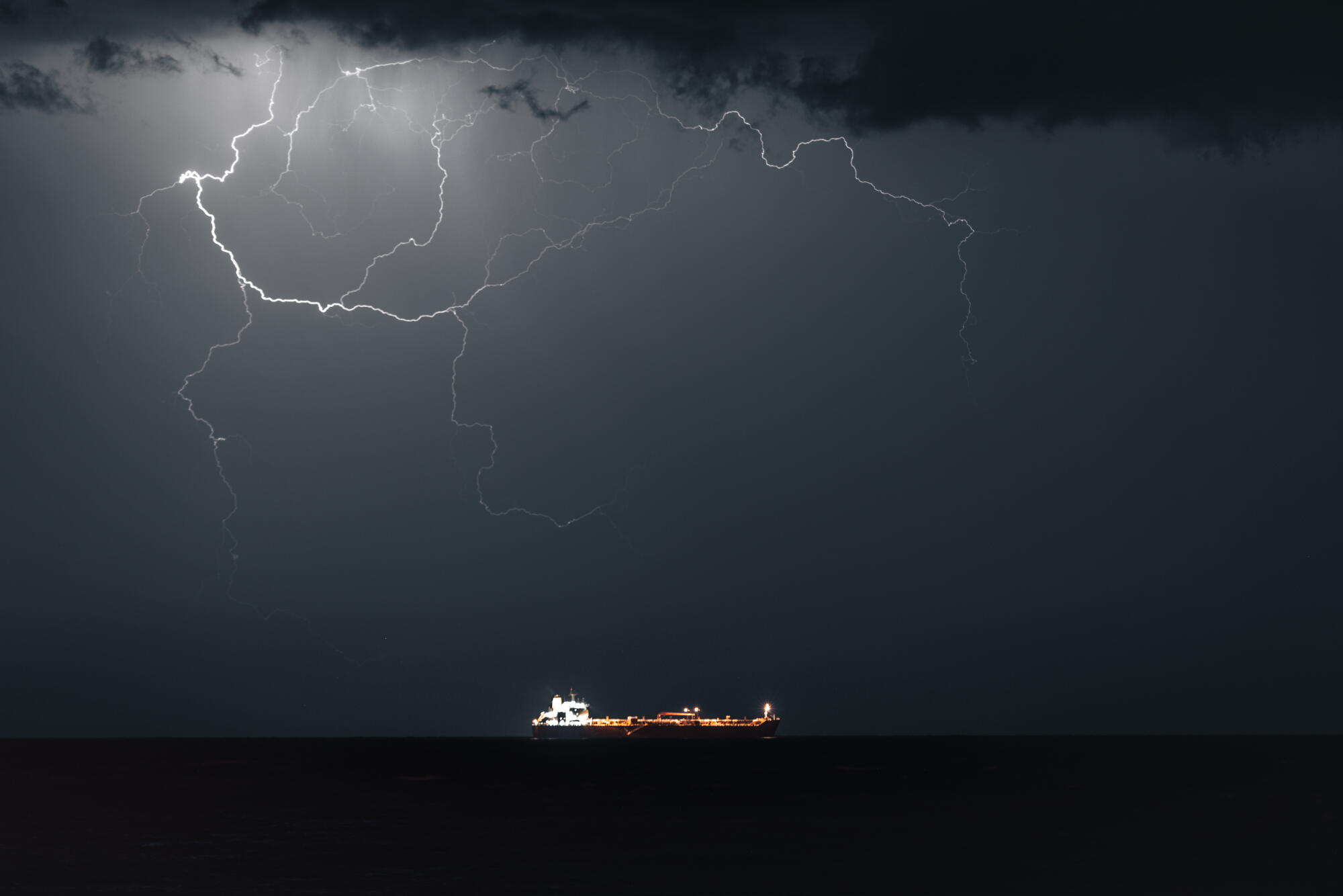 Lightning streaks across the sky above an oil tanker 