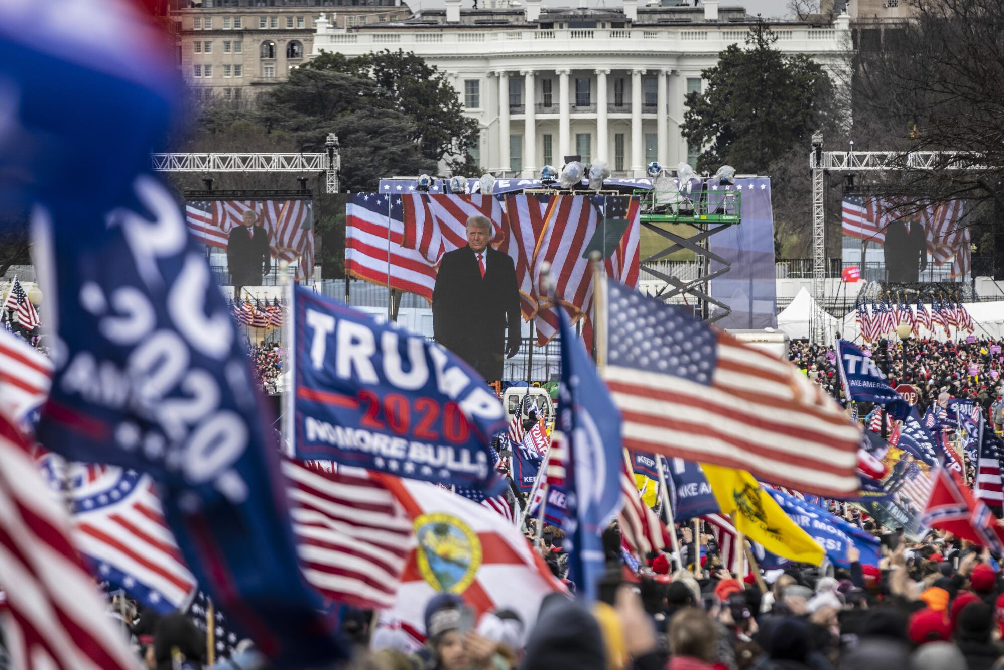 President Donald Trump is seen on a screen as his supporters cheer during a rally on the National Mall