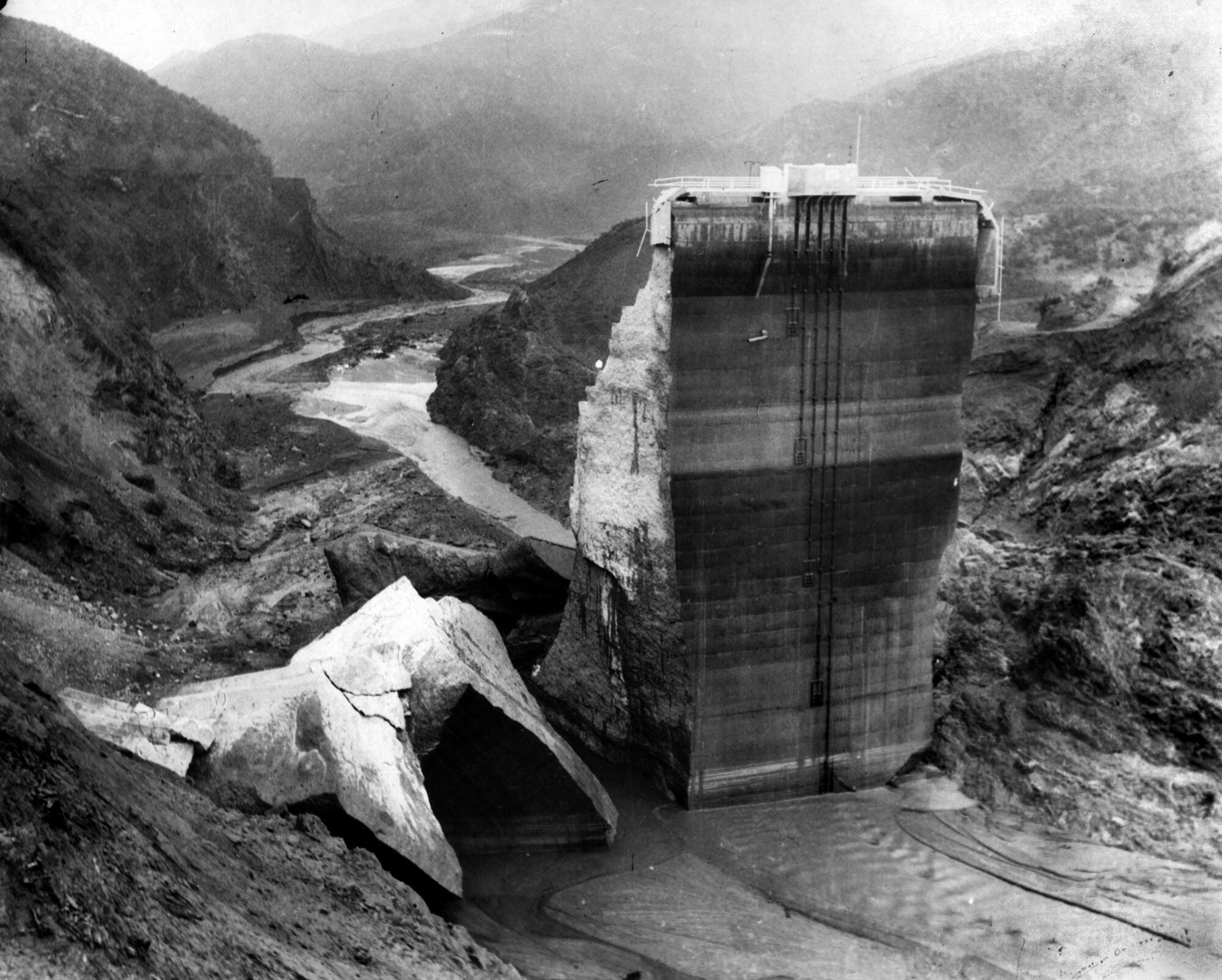 March 1928: The remaining section of the St. Francis Dam with crumbled sections at its base.