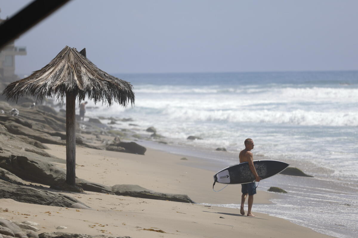 A surfer looks out at the ocean from Thalia Street Beach in Laguna Beach