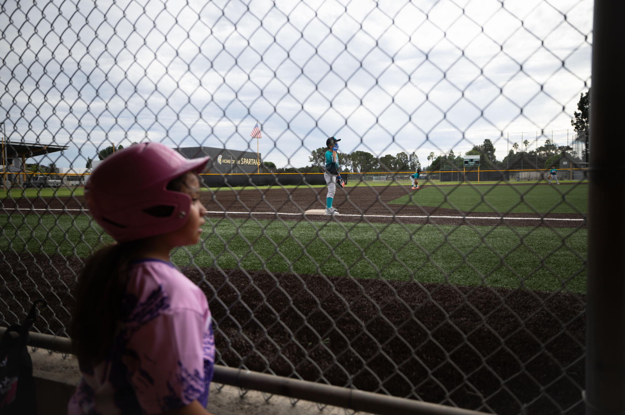 A Little League player waits for her turn to bat.