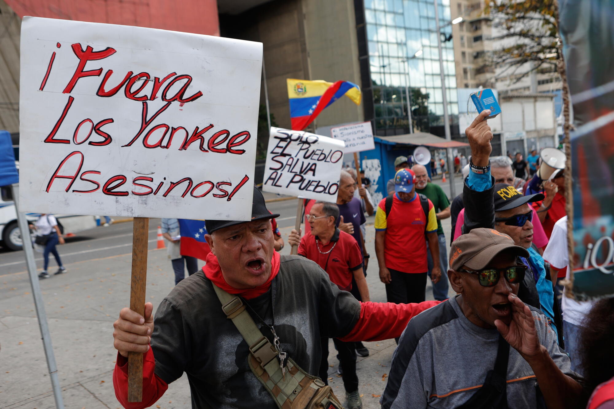 A man holds a sign with a message that reads in Spanish; "Yankee out, murderers" during a protest