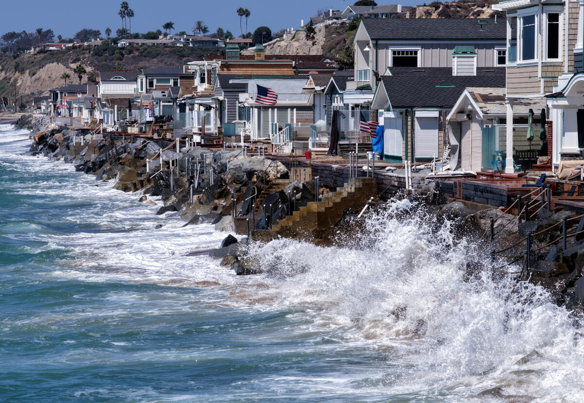 Waves crash along Capistrano Beach, where large boulders are used to protect homes.