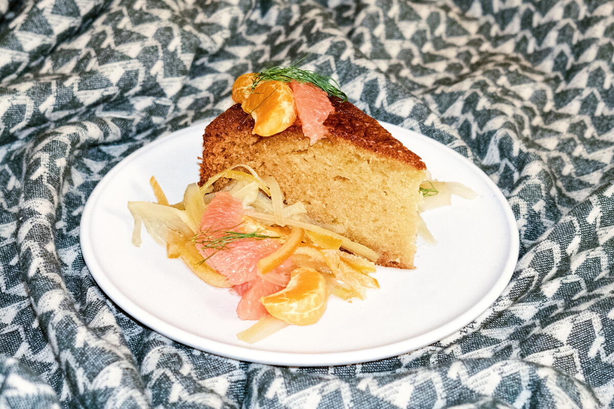 Closeup of a piece of cake on a white plate, which sits on a blue and white patterned cloth.