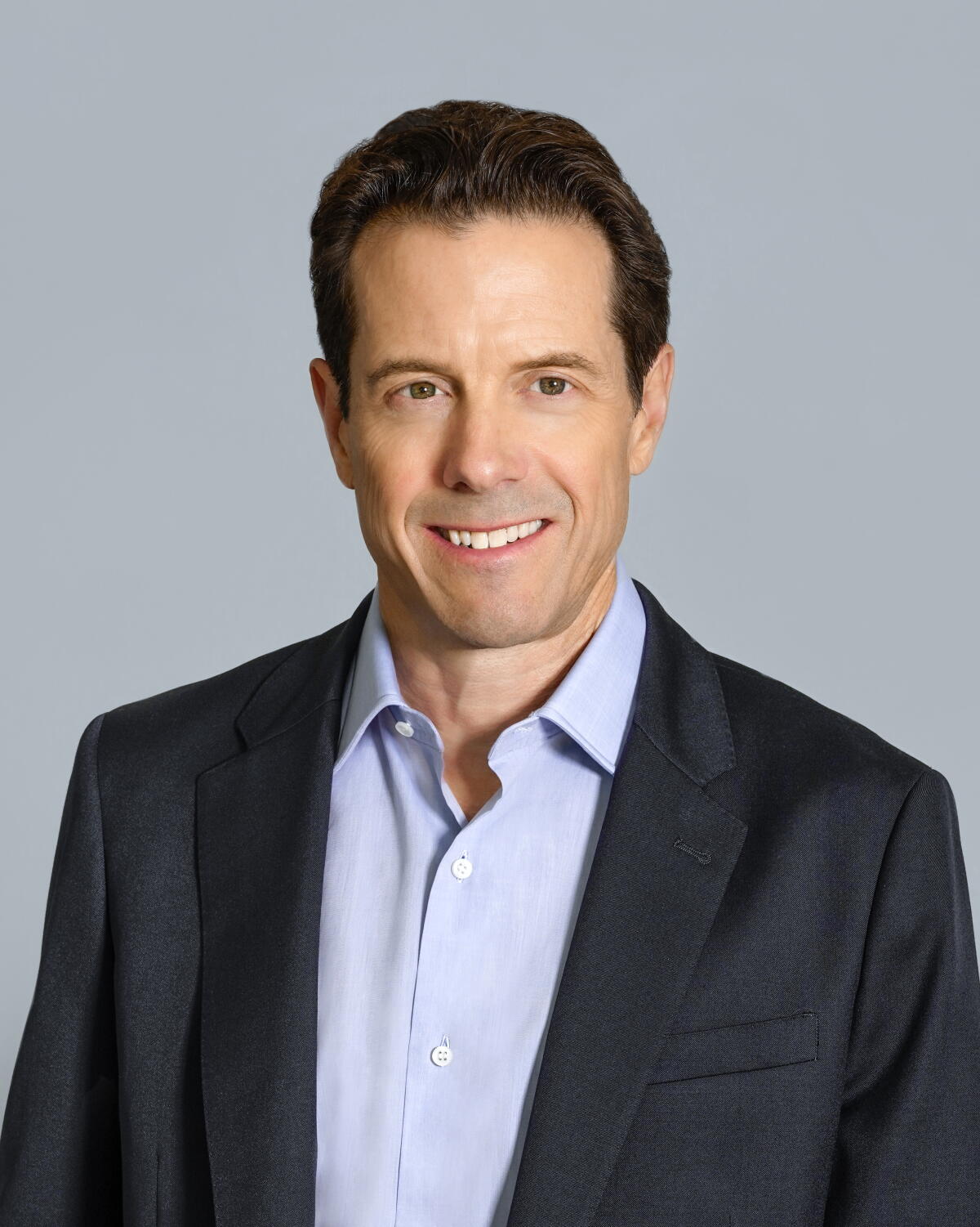 A man in a suit without a tie smiles.
