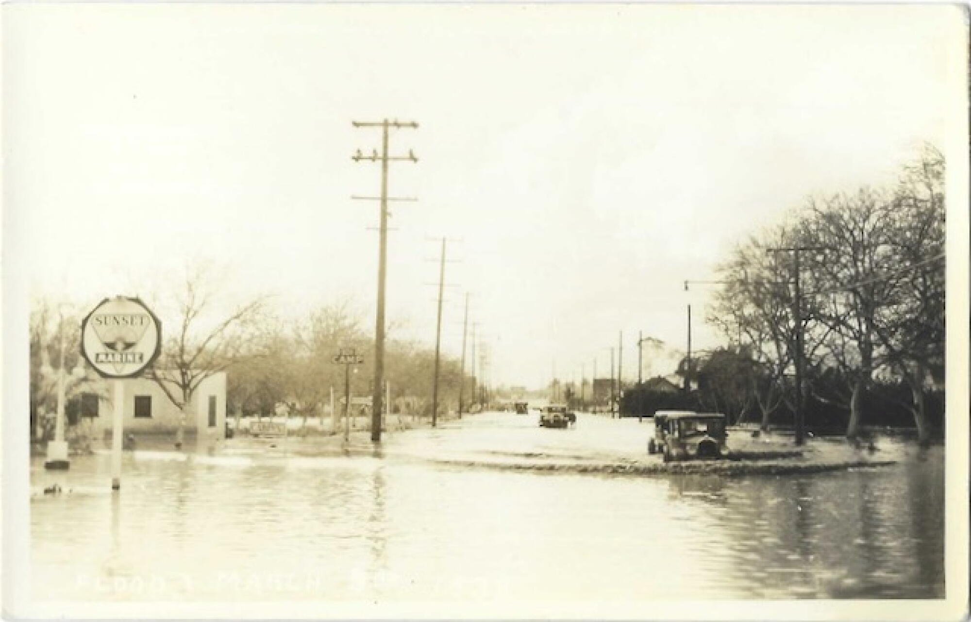 Cars make waves in a flooded street on a sepia tone vintage postcard