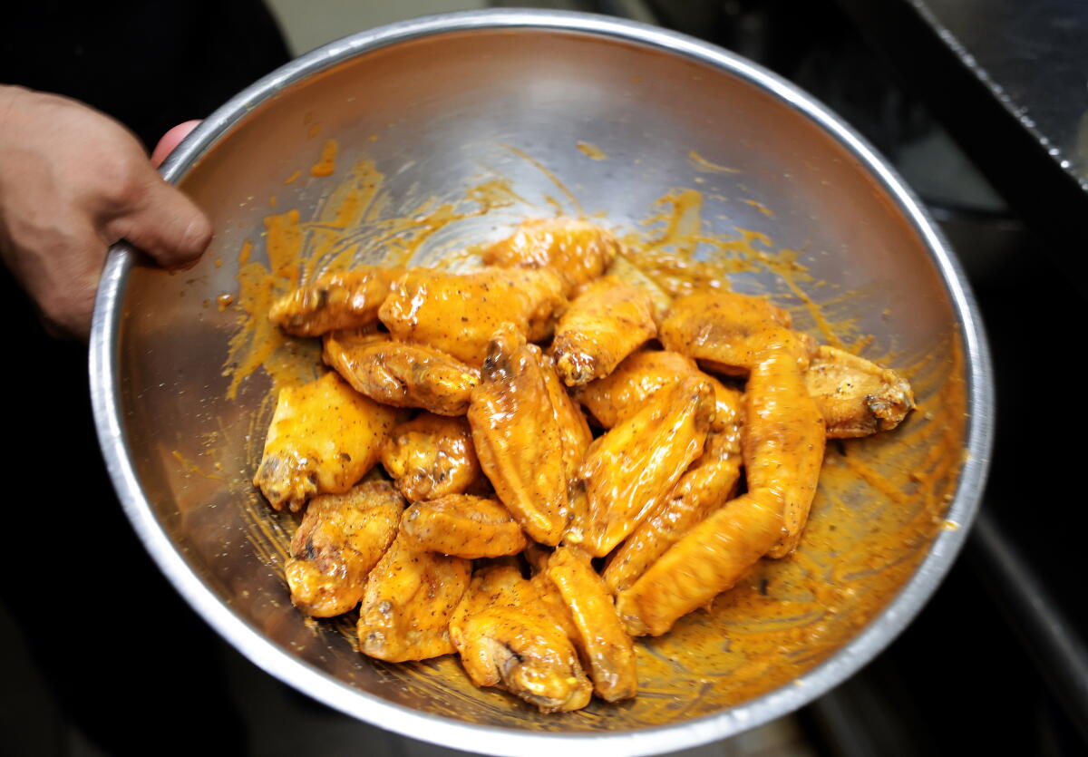 Close-up of seasoned chicken wings in a mixing bowl