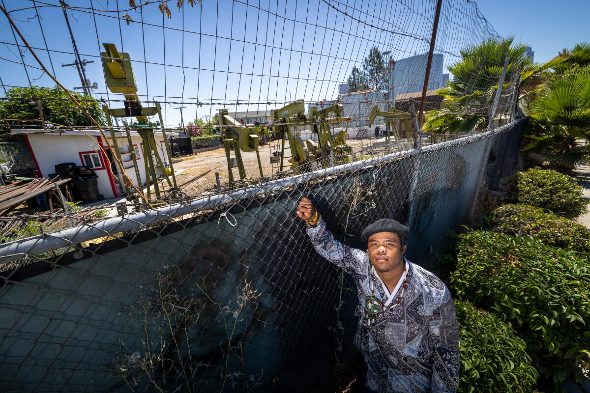 Climate activist Sim Bilal stands next to pumps at an oil field in Los Angeles in 2024.