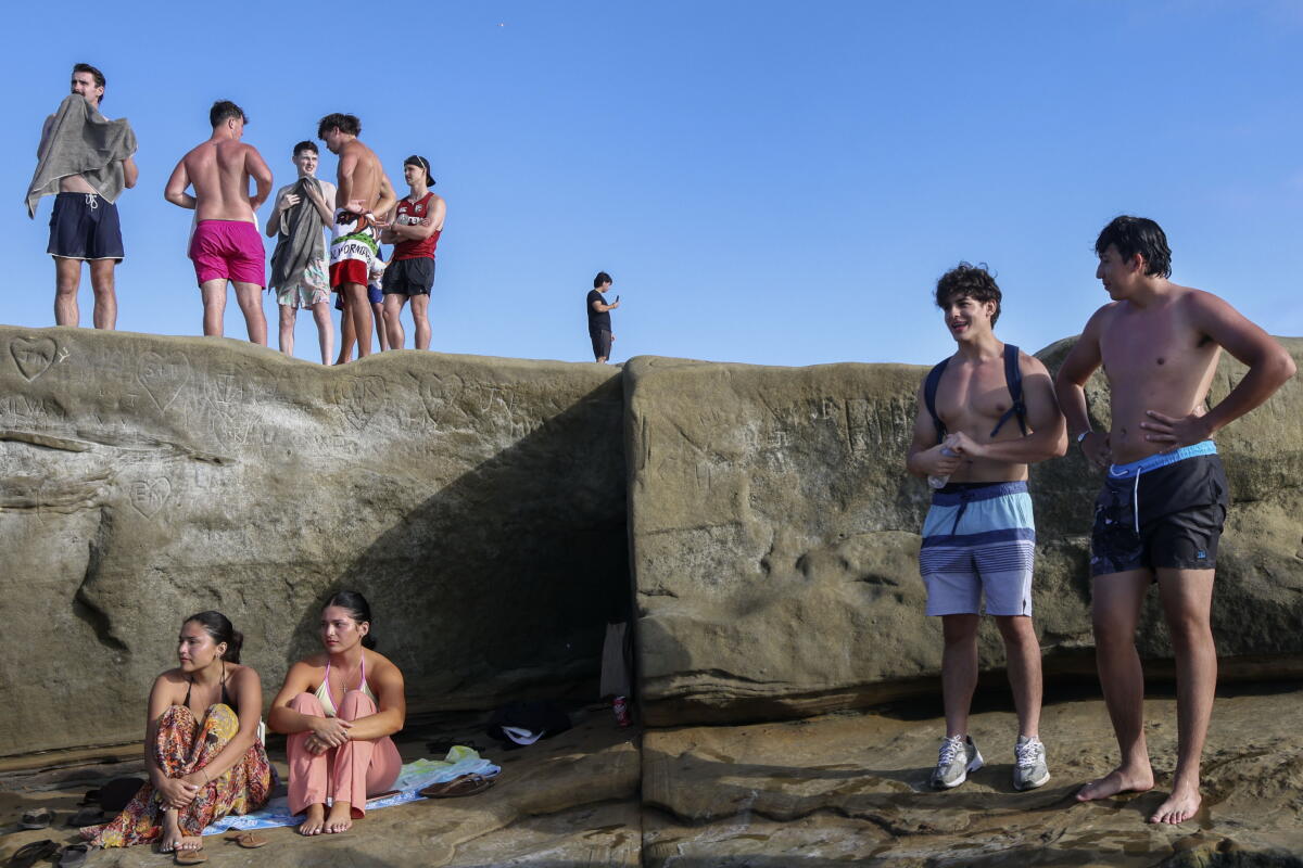 Spectators watch people jump into the water at Sunset Cliffs in the Ocean Beach area of San Diego.